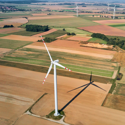 Landschaft mit braunen Feldern und weißen Windrädern in Deutschland